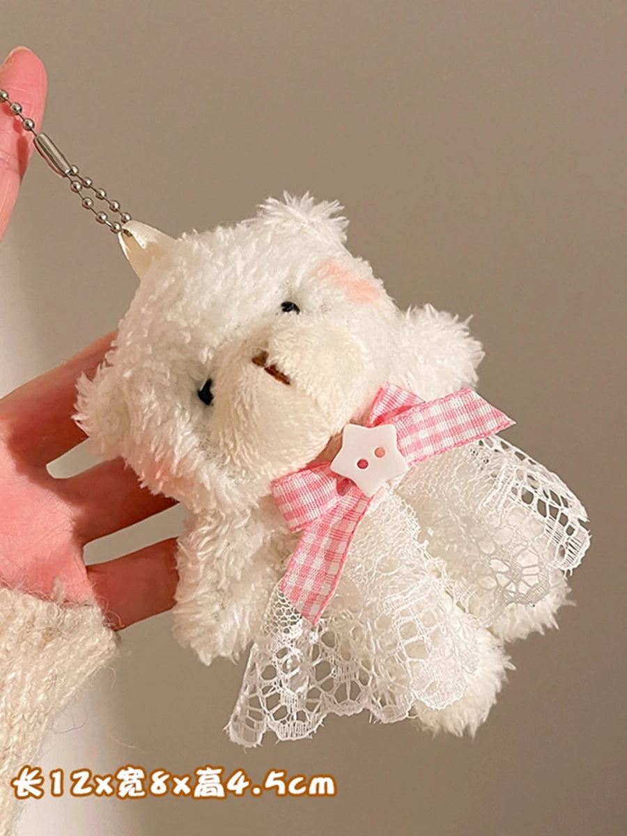 A white plush bear keychain featuring a camera and glasses, held by a hand.
