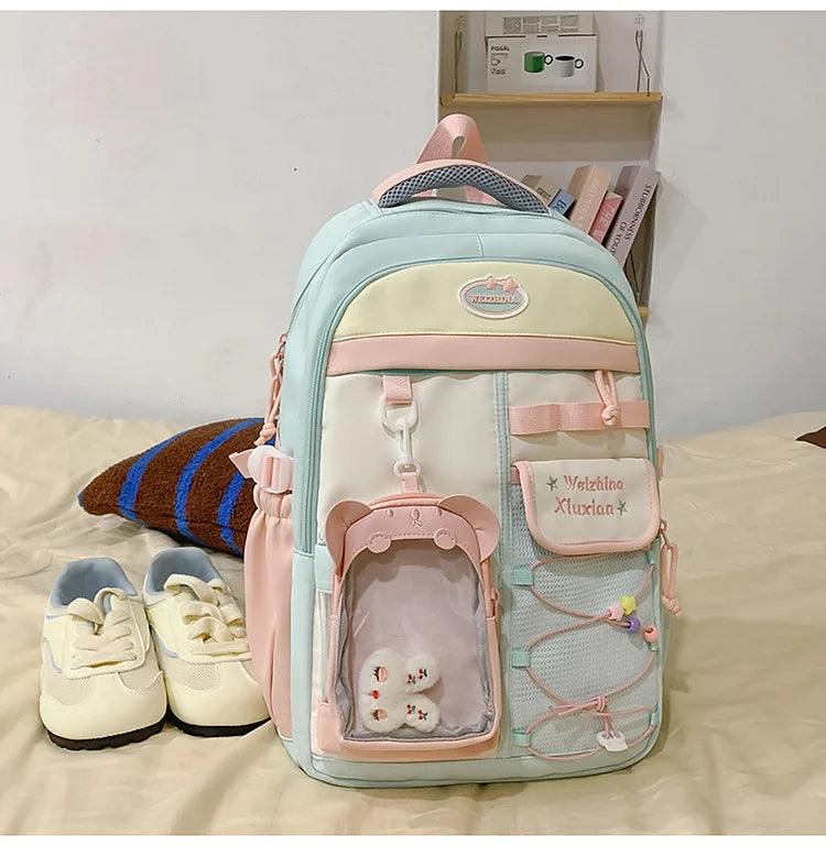 A light blue and pink Candy Color Campus backpack for women sitting on a beige surface.