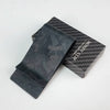 A black carbon fiber money clip is displayed inside its box with a textured pattern.