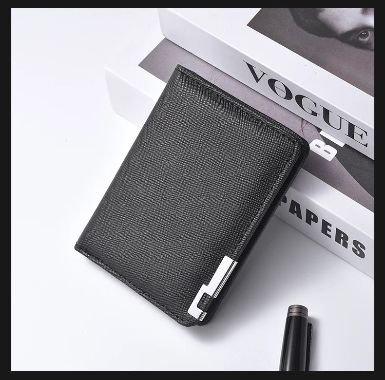 A black slim vertical men's card wallet resting on a white surface next to a magazine.