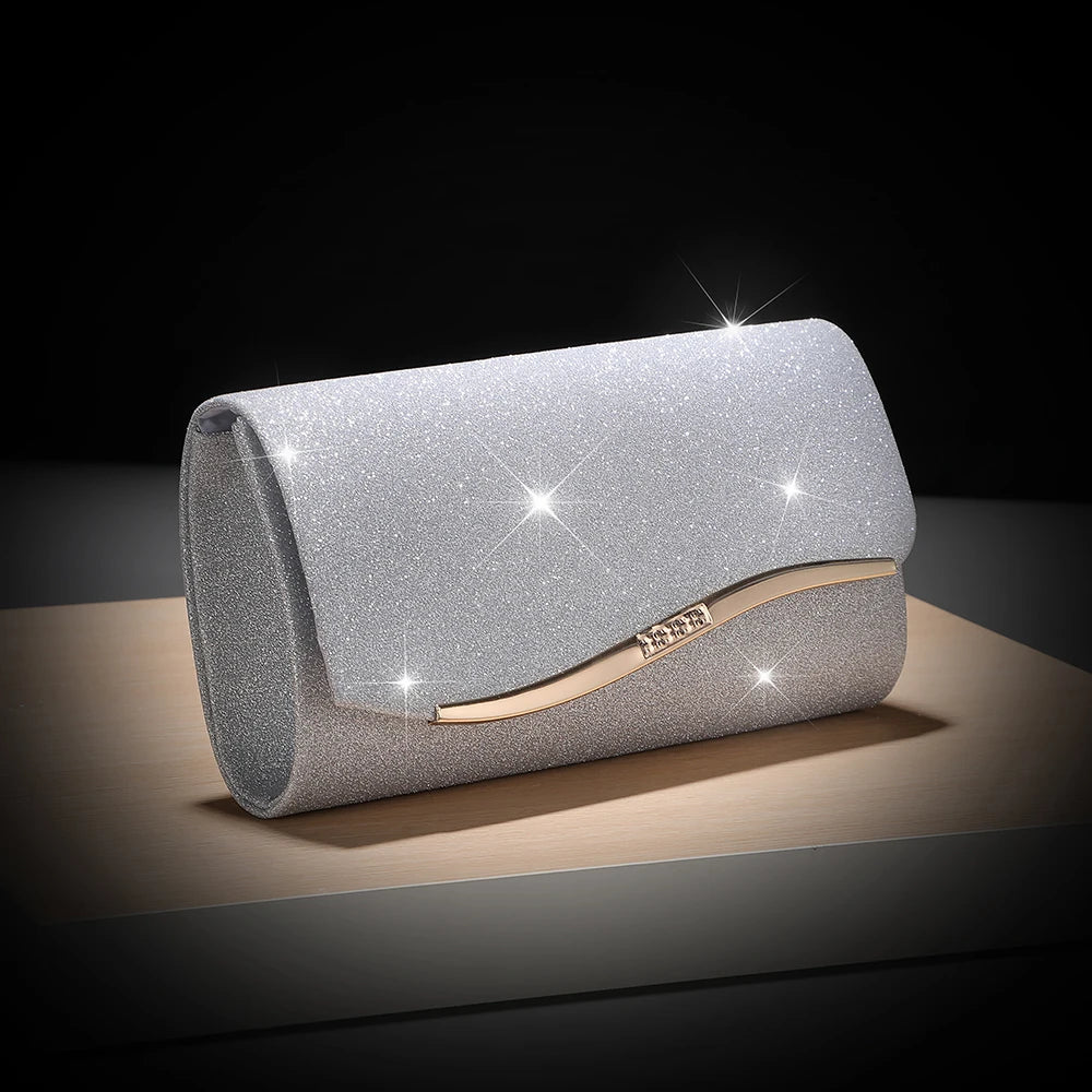 Silver sequined envelope clutch with a gold chain resting on a wooden surface.
