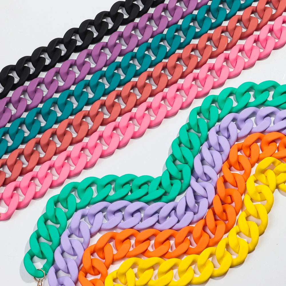 A close-up of a colorful matte acrylic choker necklace featuring multiple strands in shades of black, purple, teal, pink, and