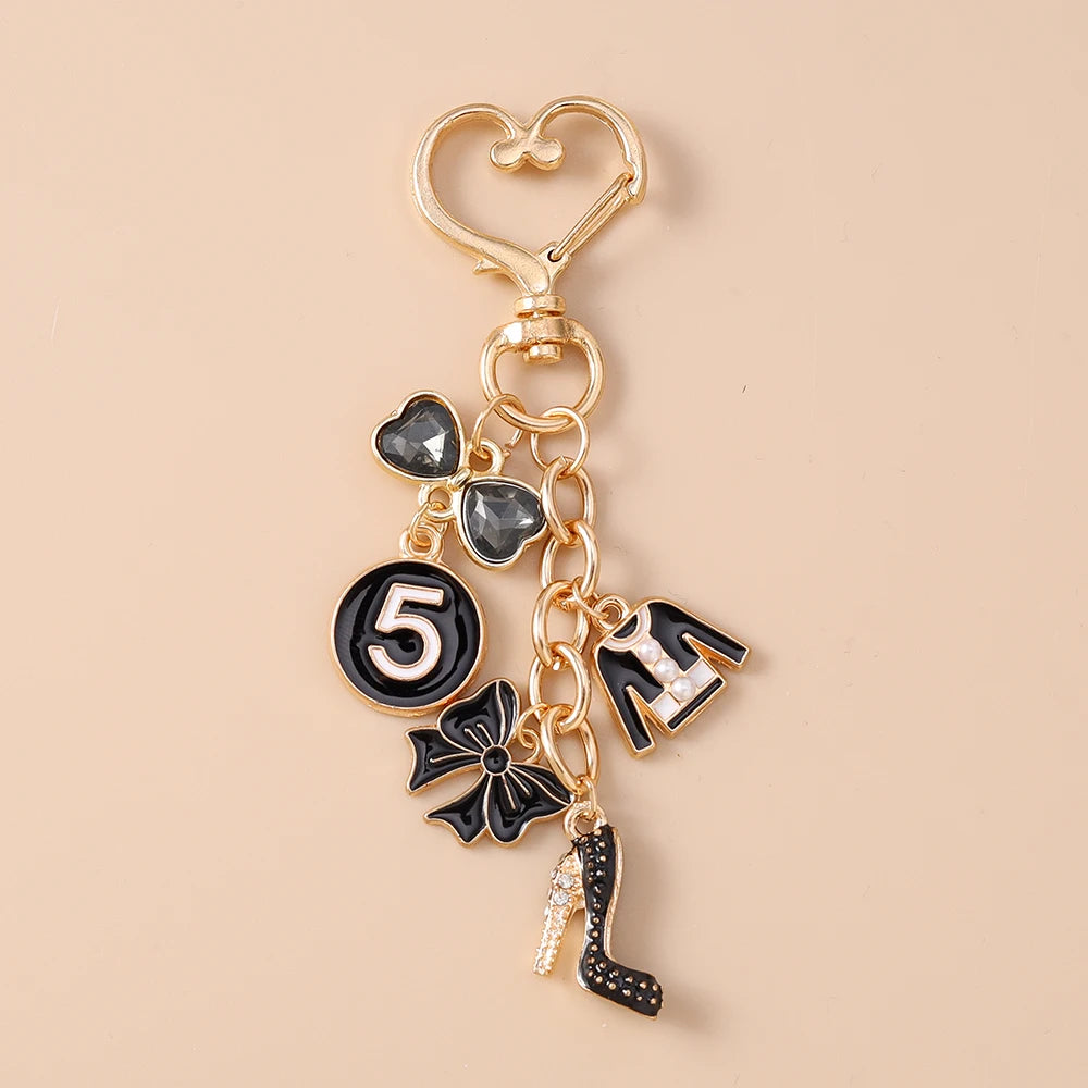 Gold enamel heart keychain featuring a number five charm and a black bow and shoe charm