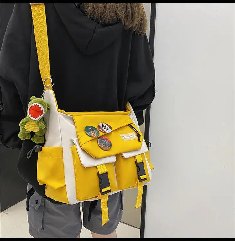 A yellow and white nylon crossbody shoulder bag with green charm and black fabric worn by a person.