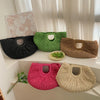A collection of woven rattan half-moon beach handbags in various shades of green, brown, and pink displayed on a white shelf.