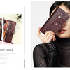 A woman holds a dark brown genuine leather vintage clutch wallet in a diagonal angle against a striped top.
