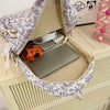 A purple and white floral quilted backpack set with a laptop inside, resting on a light wood surface.
