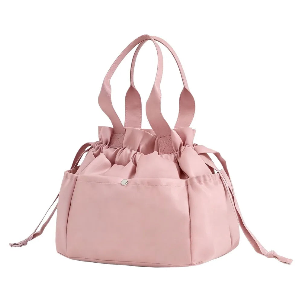 A pink insulated drawstring lunch bag with multiple pockets and fabric handles.