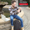 Un homme utilise un chargeur latéral assis sur une corniche de pierre à côté d'un ordinateur portable Apple et d'un sac anti-