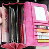 A pink clutch wallet with multiple slots and an ID window is held in a person's hand.