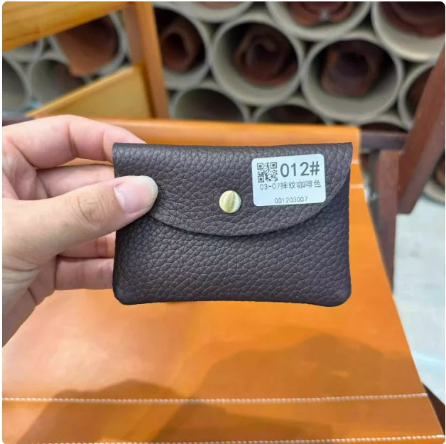 A dark brown genuine leather card holder with a gold stud and a QR code label is held in a hand.