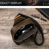 A brown genuine leather men's crossbody bag with a zippered compartment and a leather strap resting on a wooden surface.