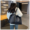 A person wearing a white hoodie and cap is holding a dark blue Versatile Oxford Cloth Travel Tote Bag.
