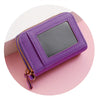 A purple fashion tassel short wallet with a clear window and gold zipper pull shown on a pink background.