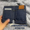 A dark blue denim foldable mini wallet and card holder is shown against a gray fabric background.