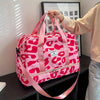 A pink leopard print nylon travel duffle bag being held by a person against a white wall.