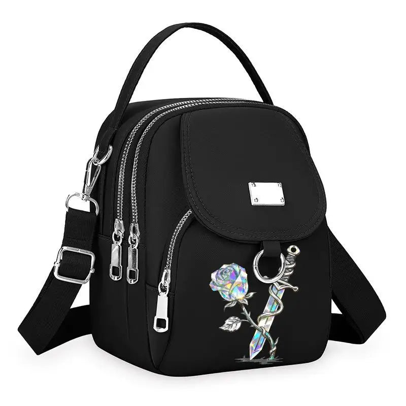 Sac bandoulière floral noir et durable avec fermeture éclair et quincaillerie argentée.
