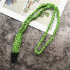 A close-up of a bright lime green hand-woven nylon lanyard with a metal hook, laid across a light-colored magazine or paper.