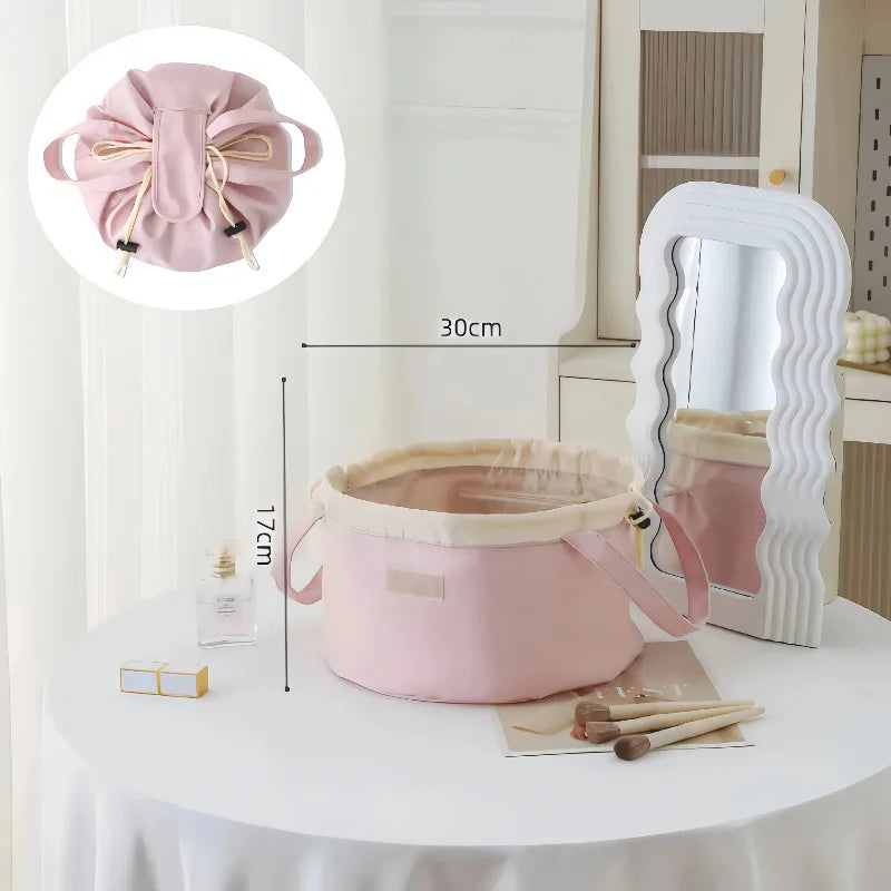 Pink instant-open flat lay makeup organizer bag with a drawstring closure displayed on a white table.