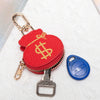 Cartera de monedas roja con diseño de signo de dólar dorado en llavero metálico y etiqueta de seguridad azul.