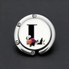Silver foldable letter Hanger hook with floral accents on a dark gray background.
