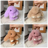 Four plush rabbit charms in purple, beige, brown, and pink colors displayed on white cards.