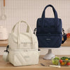 A navy blue double-layer insulated lunch bag with a handle is displayed on a wooden counter.