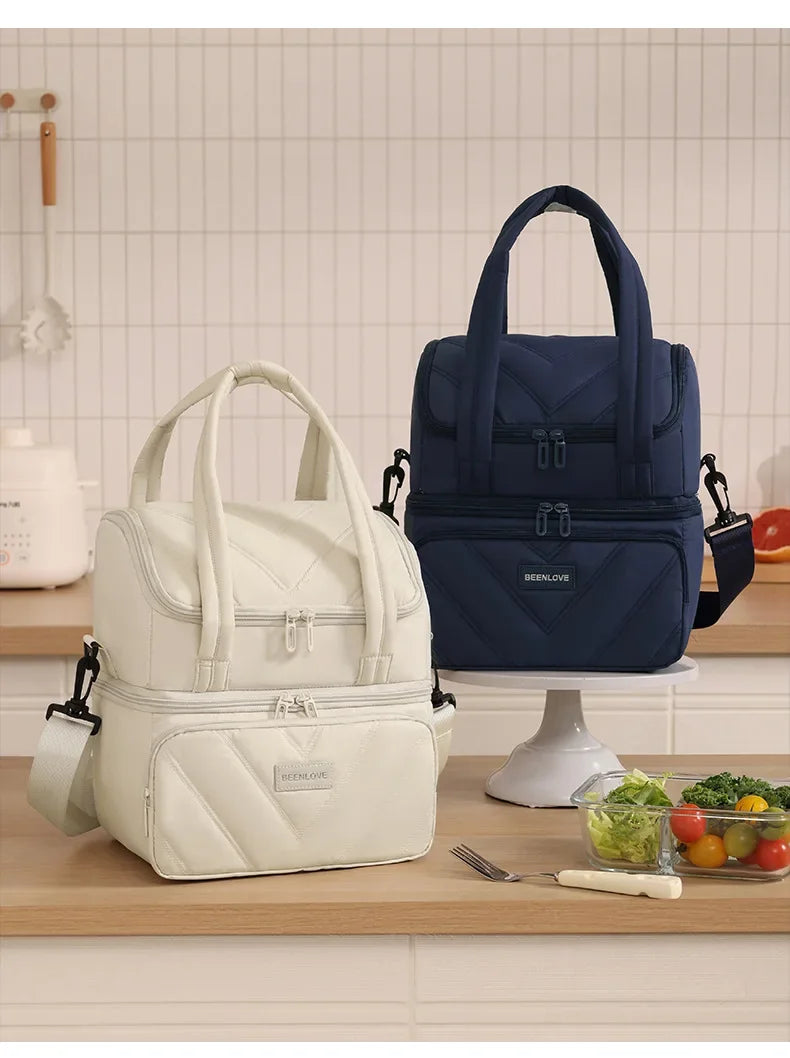 A navy blue double-layer insulated lunch bag with a handle is displayed on a wooden counter.