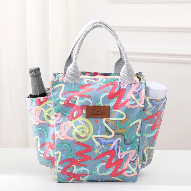 Bolsa térmica estampada colorida con asas grises, ideal para almuerzos o artículos de pañal.