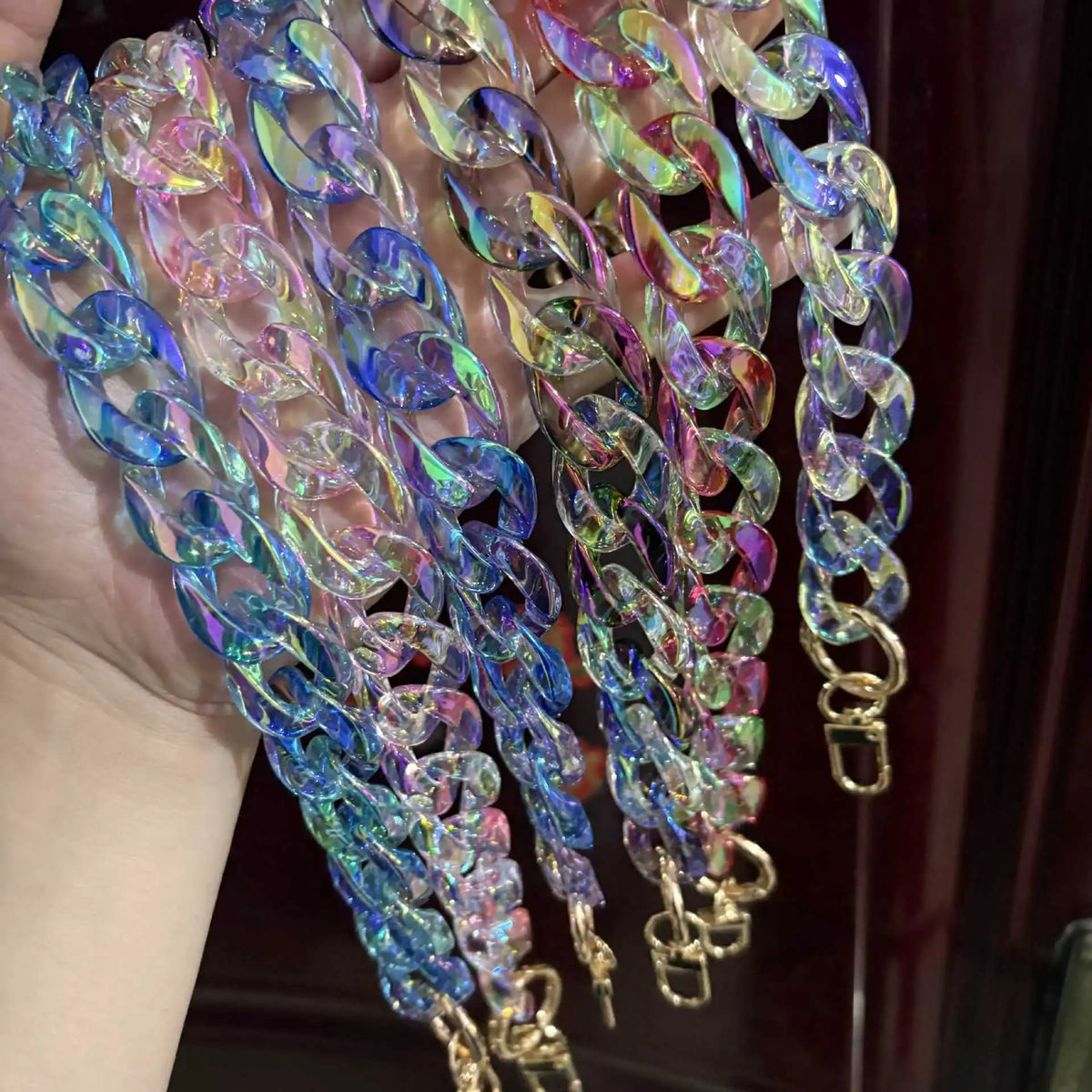 A close-up of multiple colorful resin bag straps and purse charms with iridescent blue, purple, and pink hues.