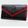 Black alligator pattern leather clutch bag with a red accent detail.