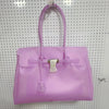Helles lila Sommer-Gelidertasche mit Henkel und silberner Hardware vor gepunktetem Hintergrund.