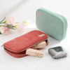 A pink corduroy pencil case with a fold-out tray and a silver metal accessory shown next to it.
