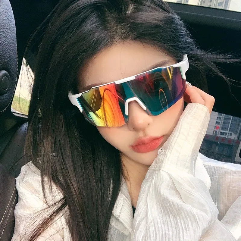 Una mujer vistiendo gafas de ciclismo coloridas en interiores con cabello largo y oscuro y una camisa blanca.