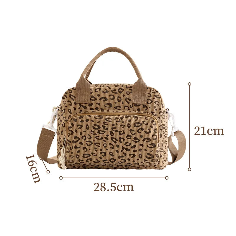 A tan floral corduroy insulated lunch bag with brown handles and a leopard print pattern.