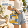A woman holds a yellow and blue geometric colorblock knitted bucket bag while wearing a cream top and denim shorts.