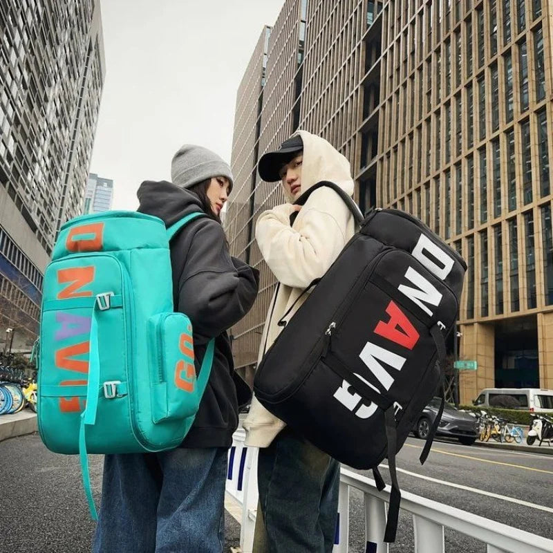 Two people stand outdoors carrying black and teal backpacks on a city street.