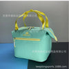 A light mint green insulated lunch bag with a yellow strap is shown against a dark background.