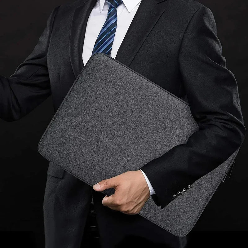 A person wearing a dark suit holds a gray waterproof canvas laptop sleeve with a soft fleece lining.