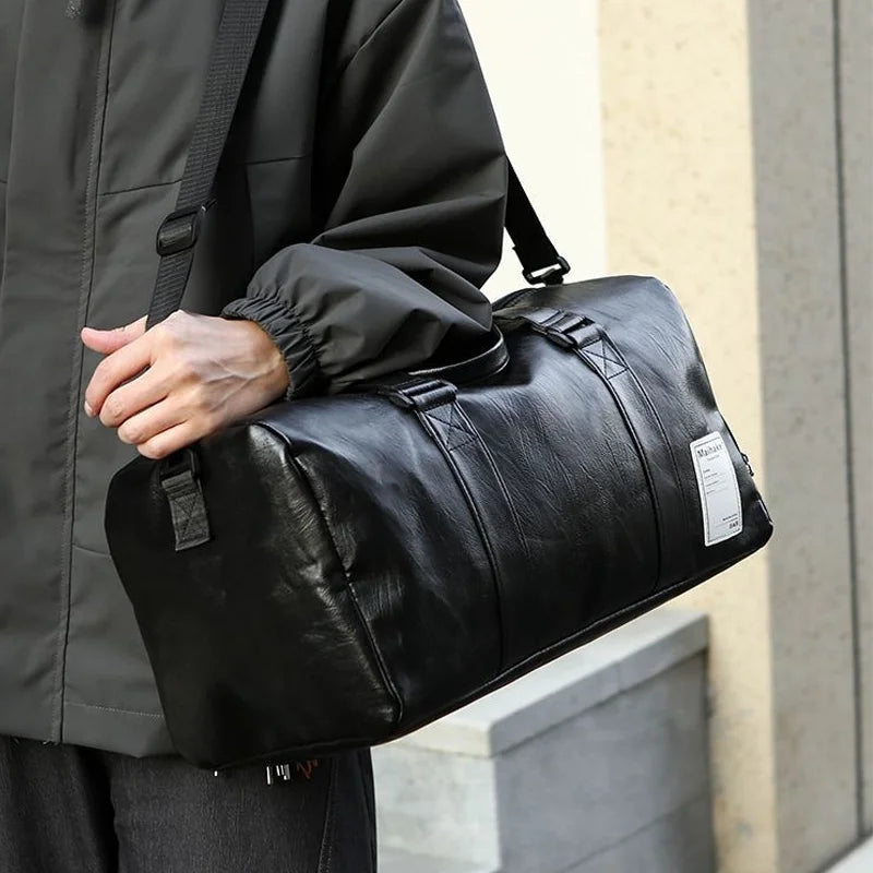 Eine Person hält eine schwarze Kunstleder-Sporttasche vor einem hellen Gebäude.