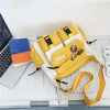 Bolso cruz de nylon amarillo y blanco casual apoyado en un teclado de portátil.