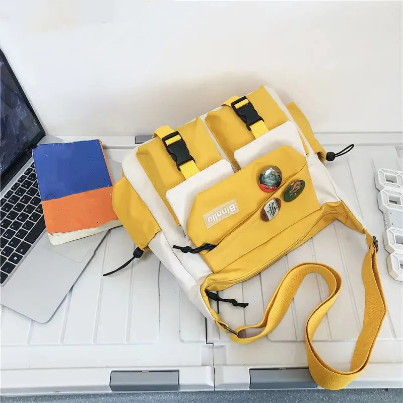 Bolso cruz de nylon amarillo y blanco casual apoyado en un teclado de portátil.