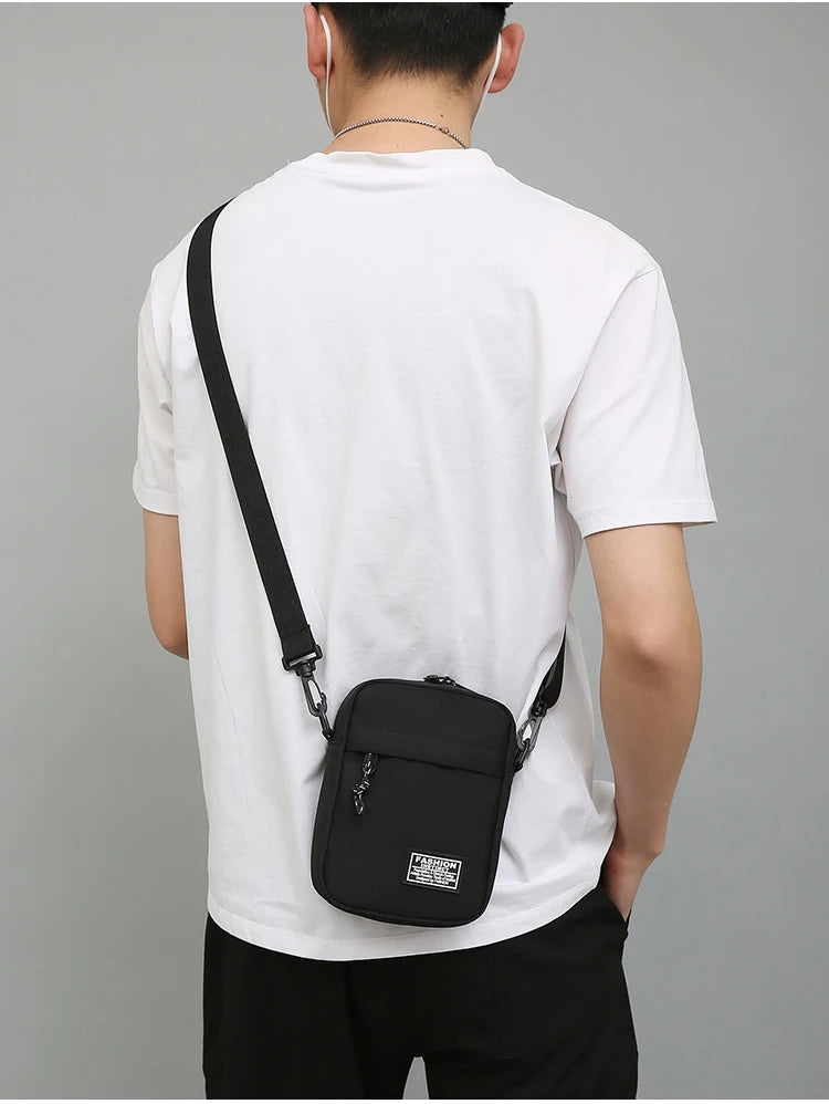 Eine Person trägt ein weißes T-Shirt mit einer schwarzen Umhängetasche, die am hinteren Hosentaschen befestigt ist.