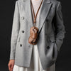 A gray blazer worn over a white top, featuring a brown leather lariat necklace and storage case.