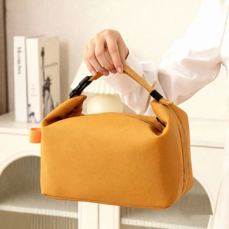 Une main tient un sac à lunch Oxford jaune moutarde isotherme sur fond blanc.