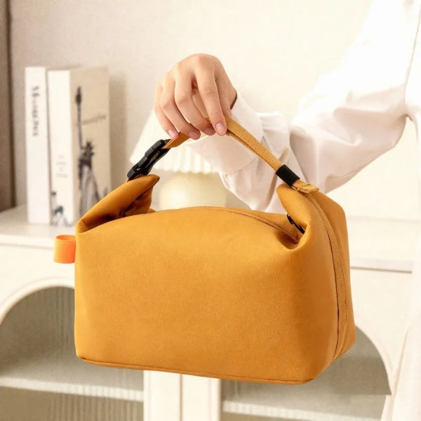 Una mano sostiene una bolsa de almuerzo Oxford aislada amarillo mostaza contra un fondo blanco.