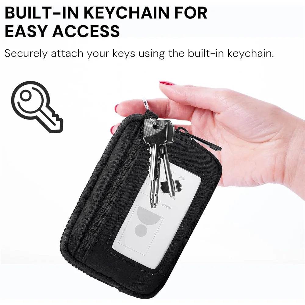 A hand is securing keys to a black zippered wallet with a built-in keychain strap.