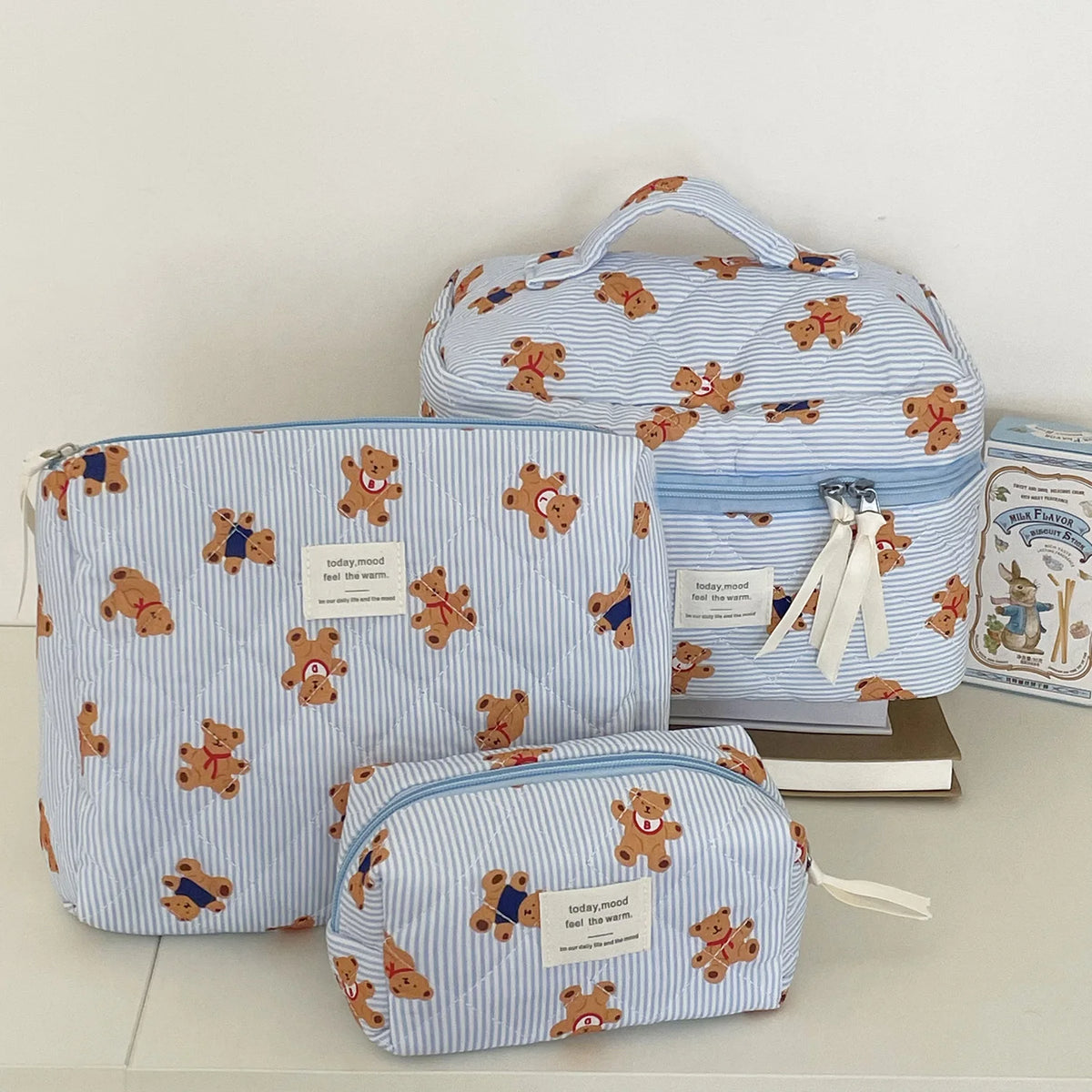 A set of striped bear cosmetic makeup bags in light blue and white fabric.