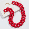 A red matte acrylic chain choker necklace is displayed on a white box.