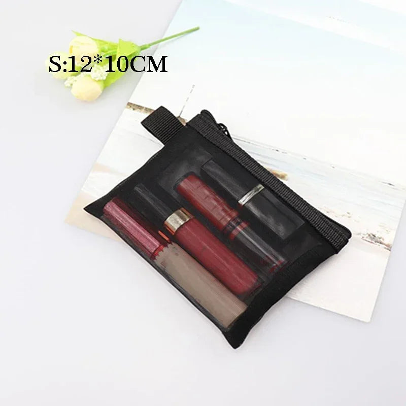 A black mesh cosmetic storage pouch containing several nail polish bottles and a small flower.